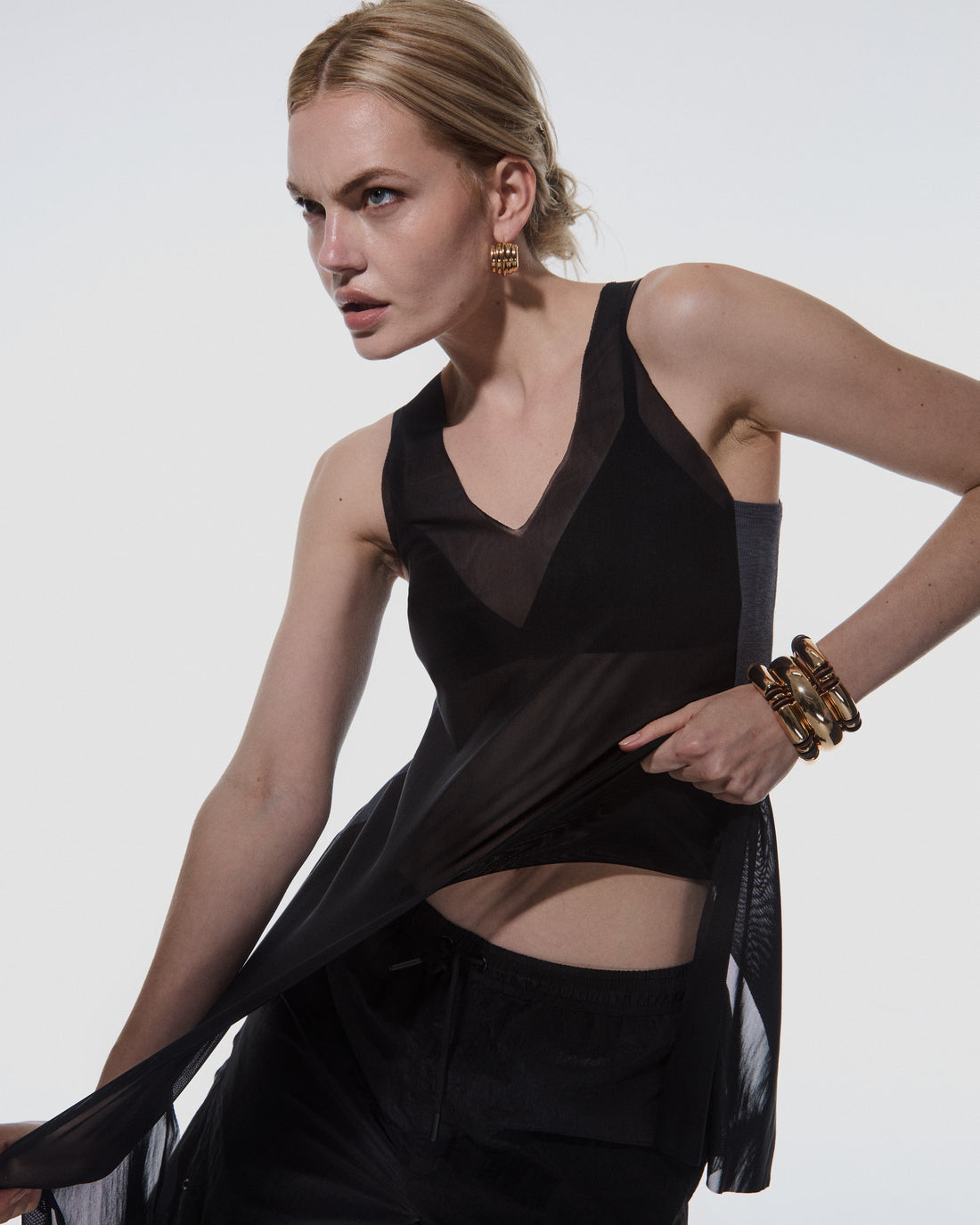 Model wearing the 12Twelve Air Dress in black layered over Track Pants, styled for a sheer, modern streetwear look in studio lighting