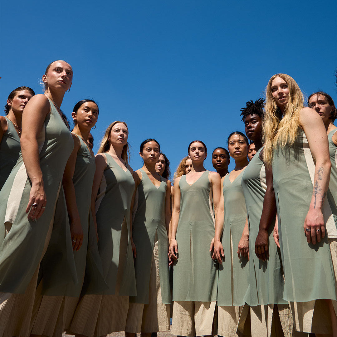 Group of women in matching dresses standing against a clear blue sky.