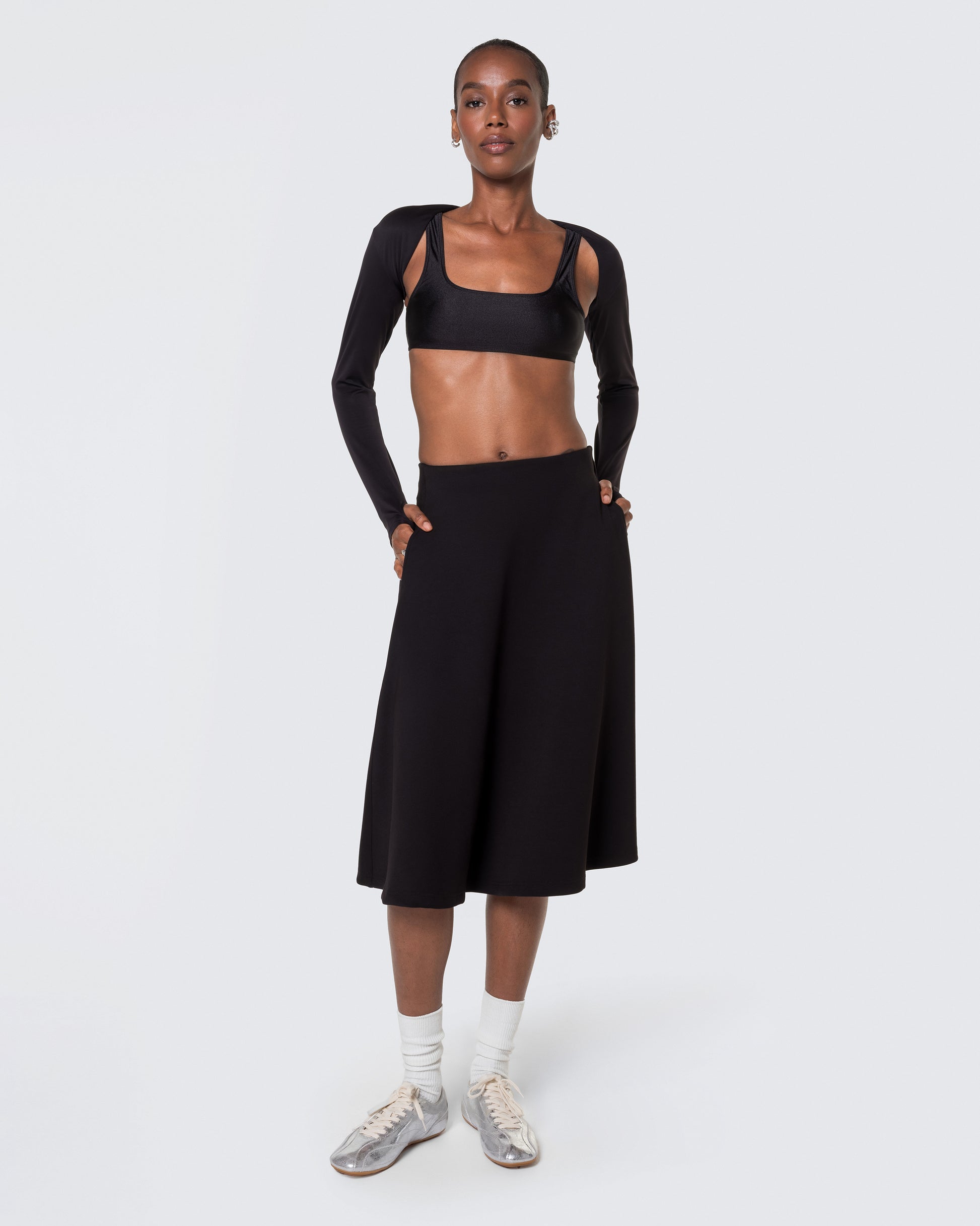Full view of the 12Twelve black midi skirt styled with white socks and sneakers