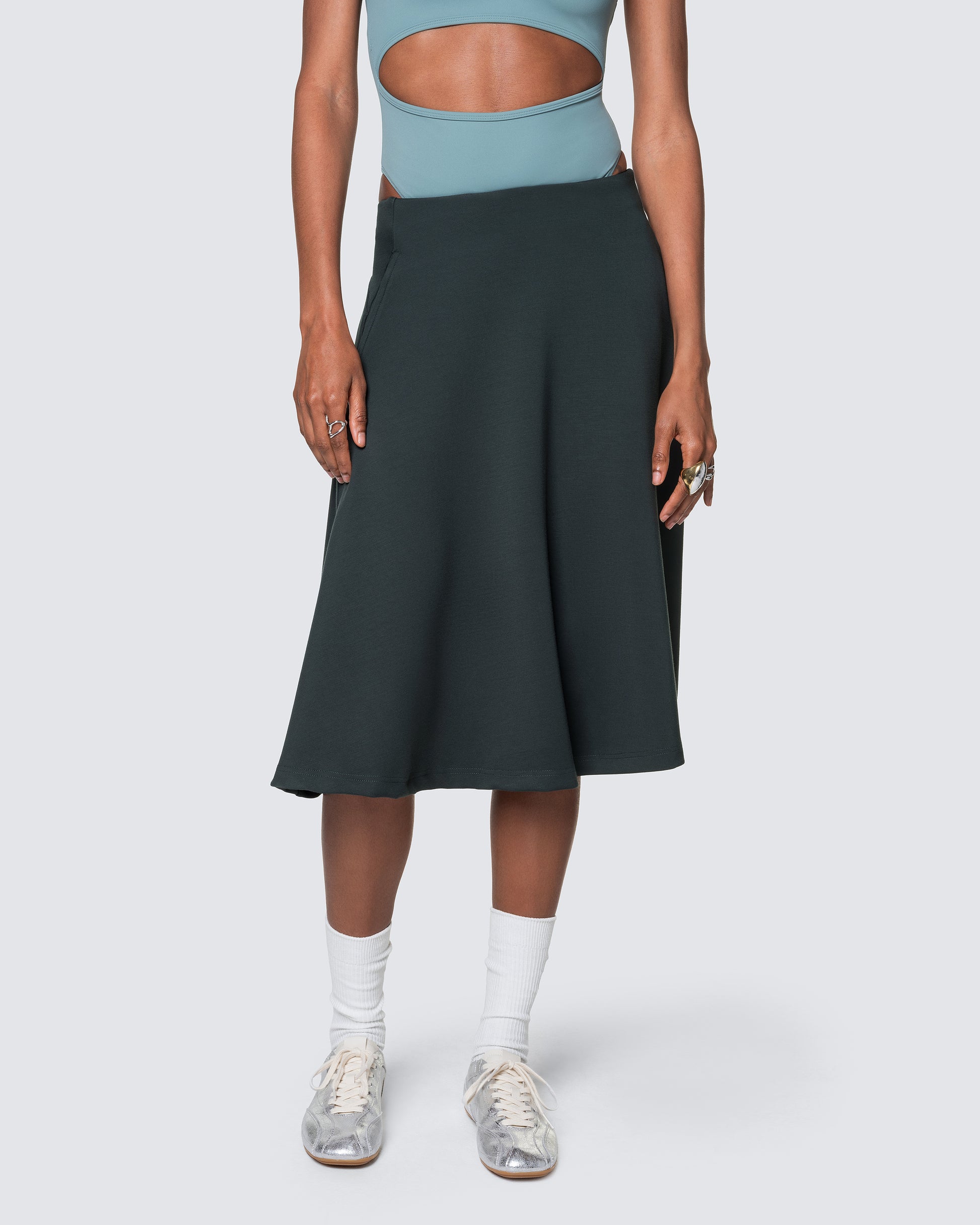 High-waisted emerald green midi skirt styled with sporty top and sneakers