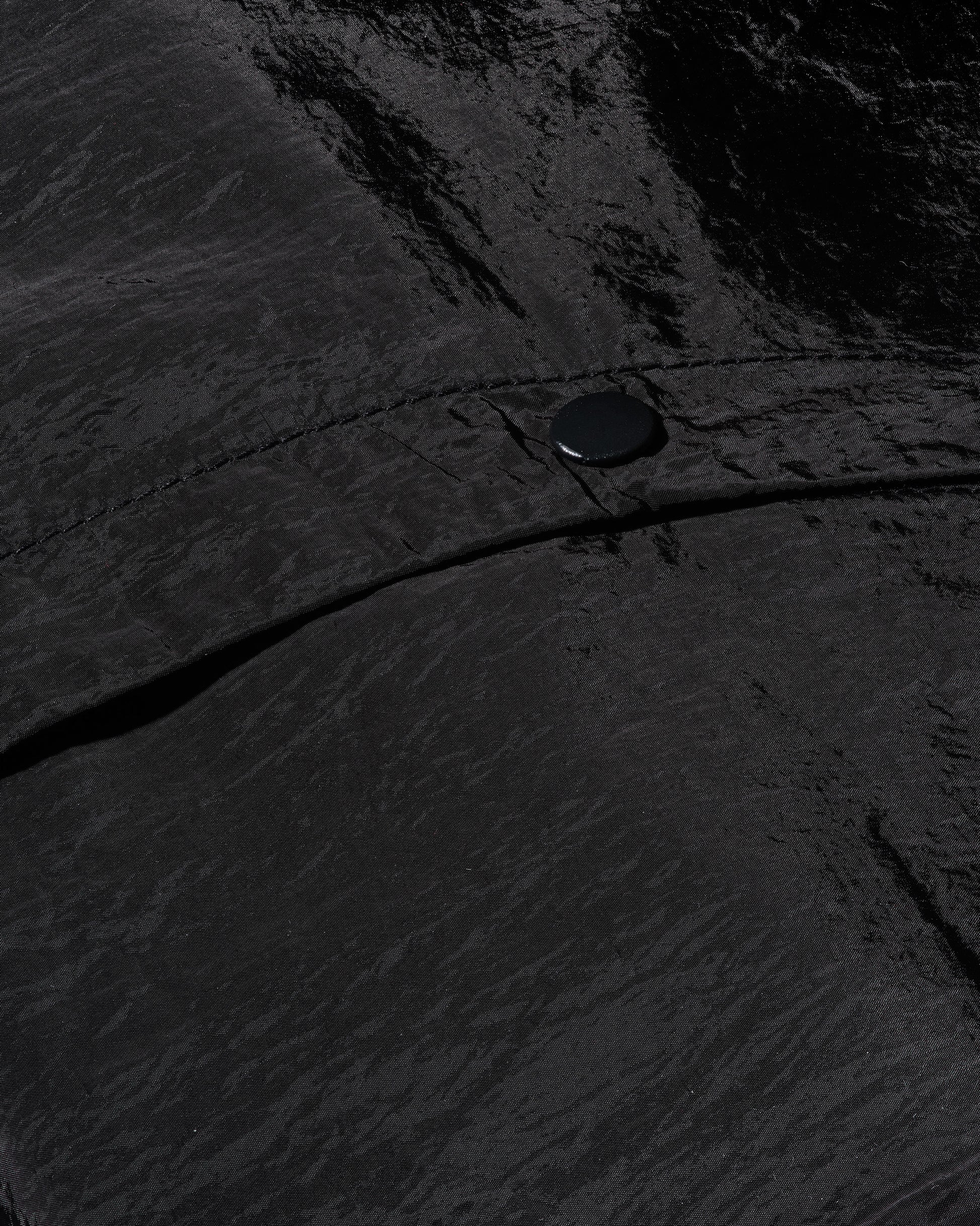 Detailed shot of 12Twelve track pants snap button and tonal seam on tech-style crinkle fabric