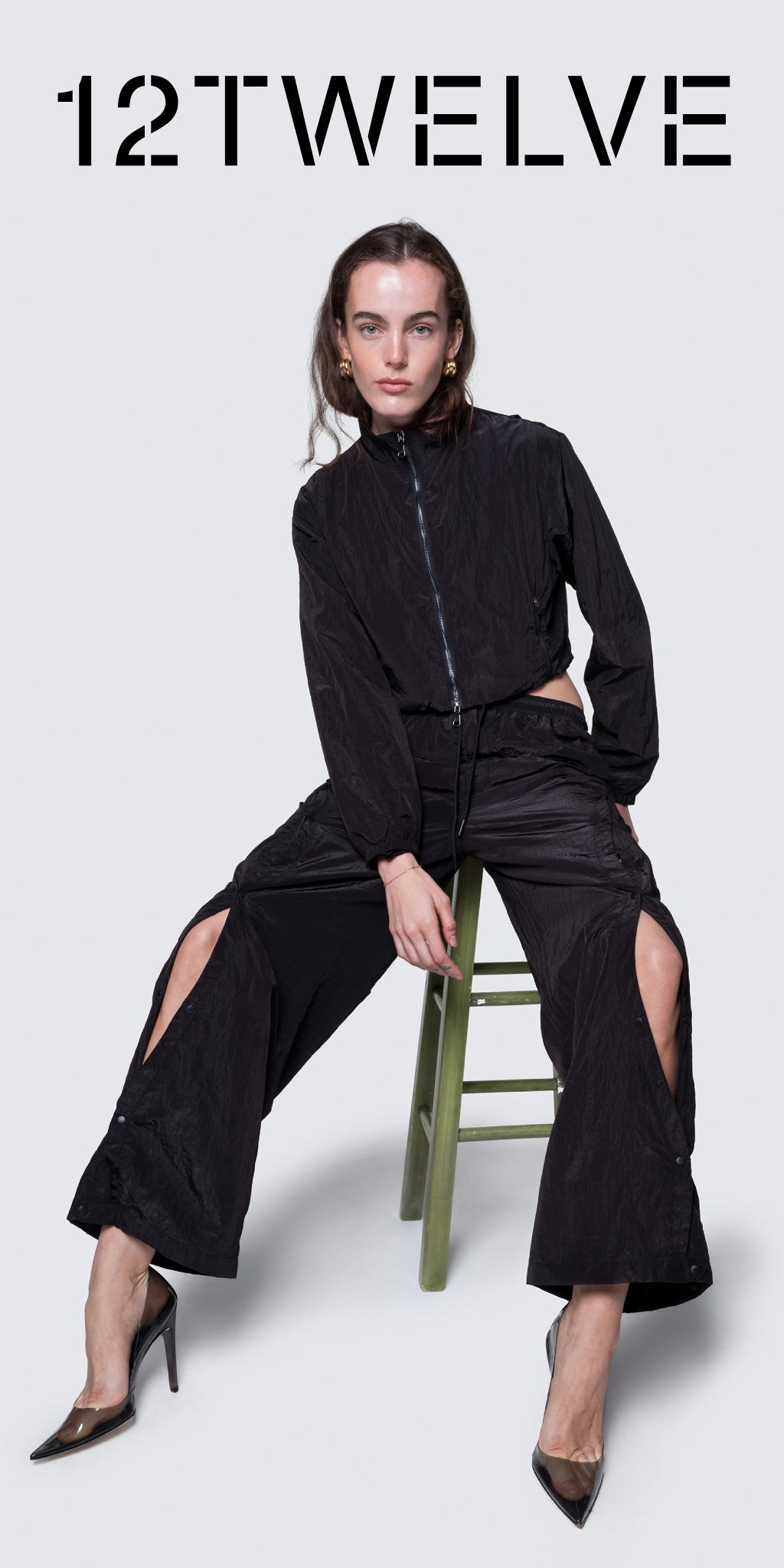 Model wearing 12Twelve’s black Track Pants and Crop Jacket set, styled with pointed heels for a modern streetwear look.