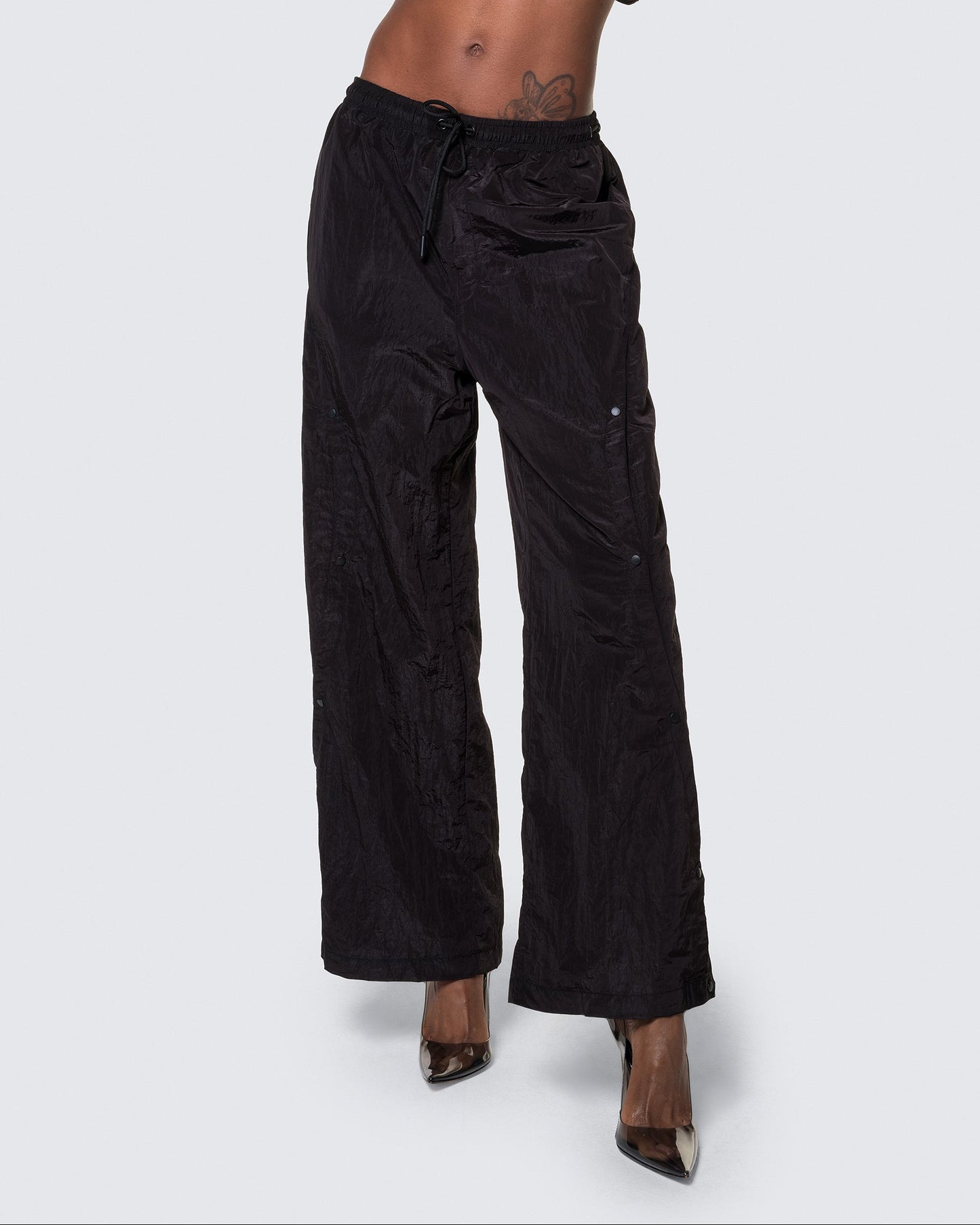 Model wearing 12Twelve black track pants with front view showcasing wide leg and drawstring waist