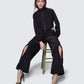 12Twelve black track pants styled with crop jacket, shown on model seated in studio setup