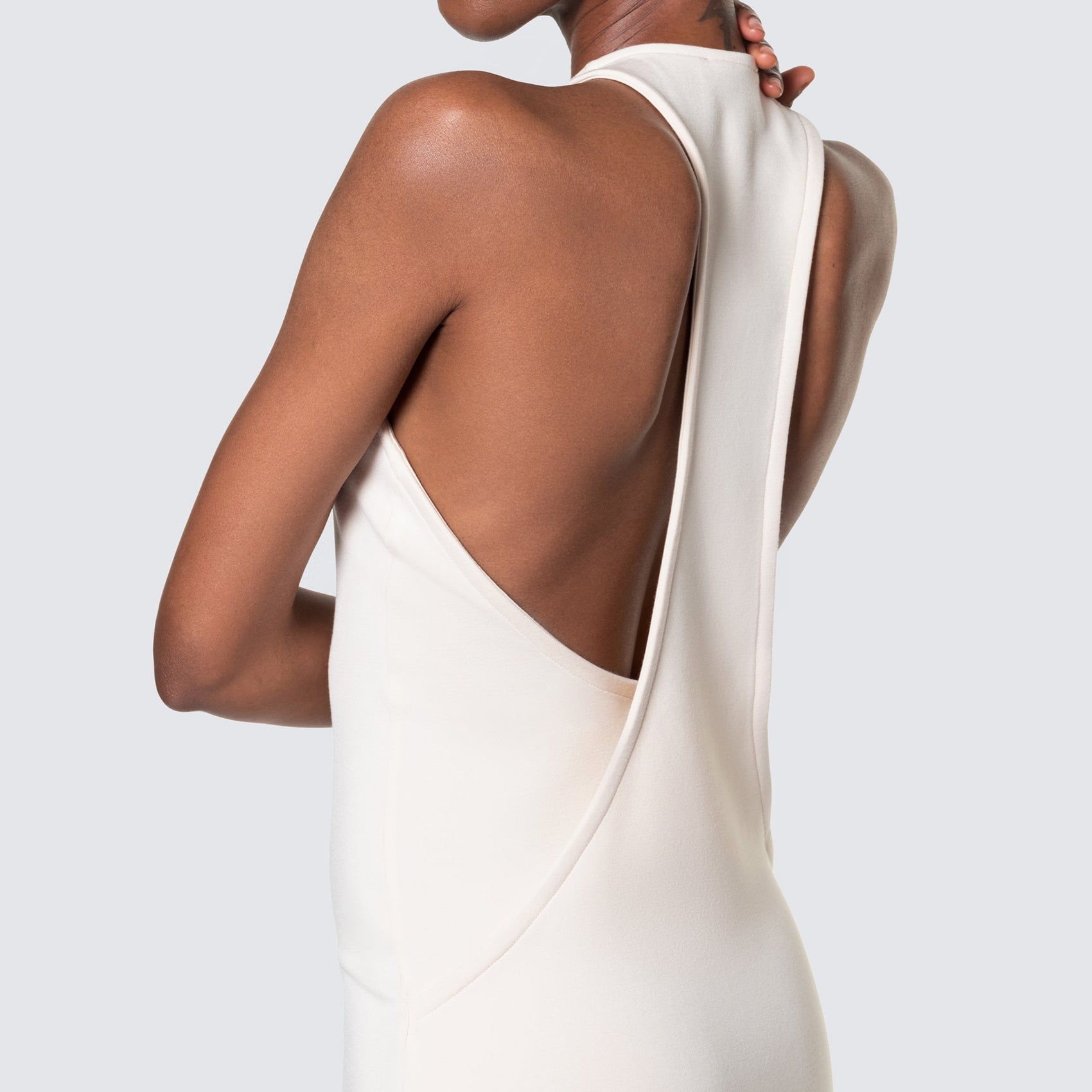A model showing the back of the 12twelve form dress in ivory highlighting the unique back design. 