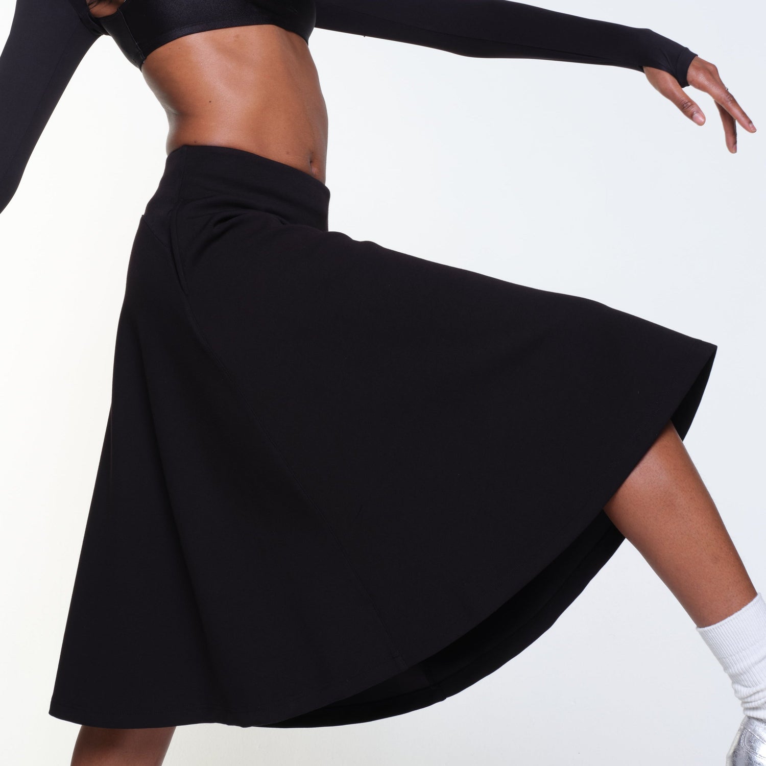 Model wearing the 12twelve Heavenly Skirt in Black with her leg and arm extended.
