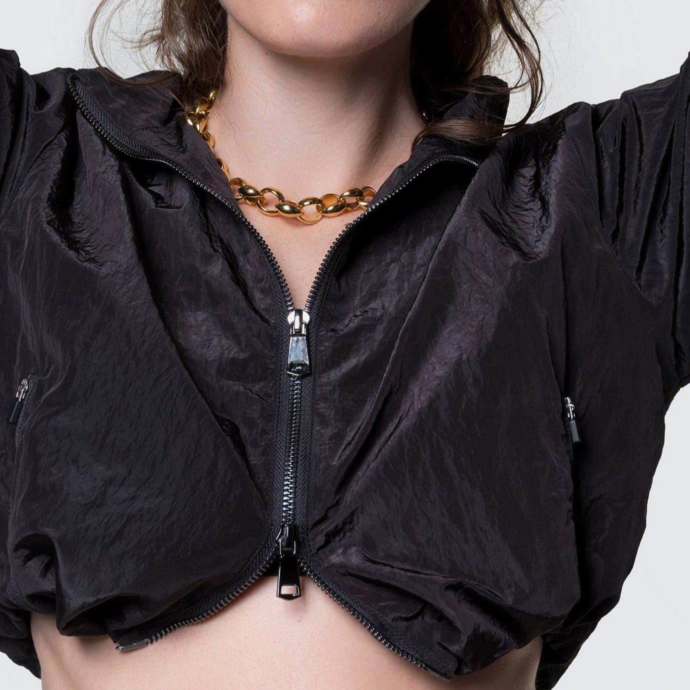 Model wearing 12twelve's nylon crop jacket in black with the two way zipper pulled up and bungees cinched to sides.